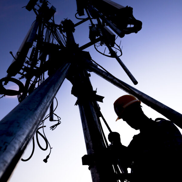silhouette,of,technician,working,on,communication,towers,in,the,dusk